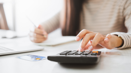 woman using calculator at desk blue bank card